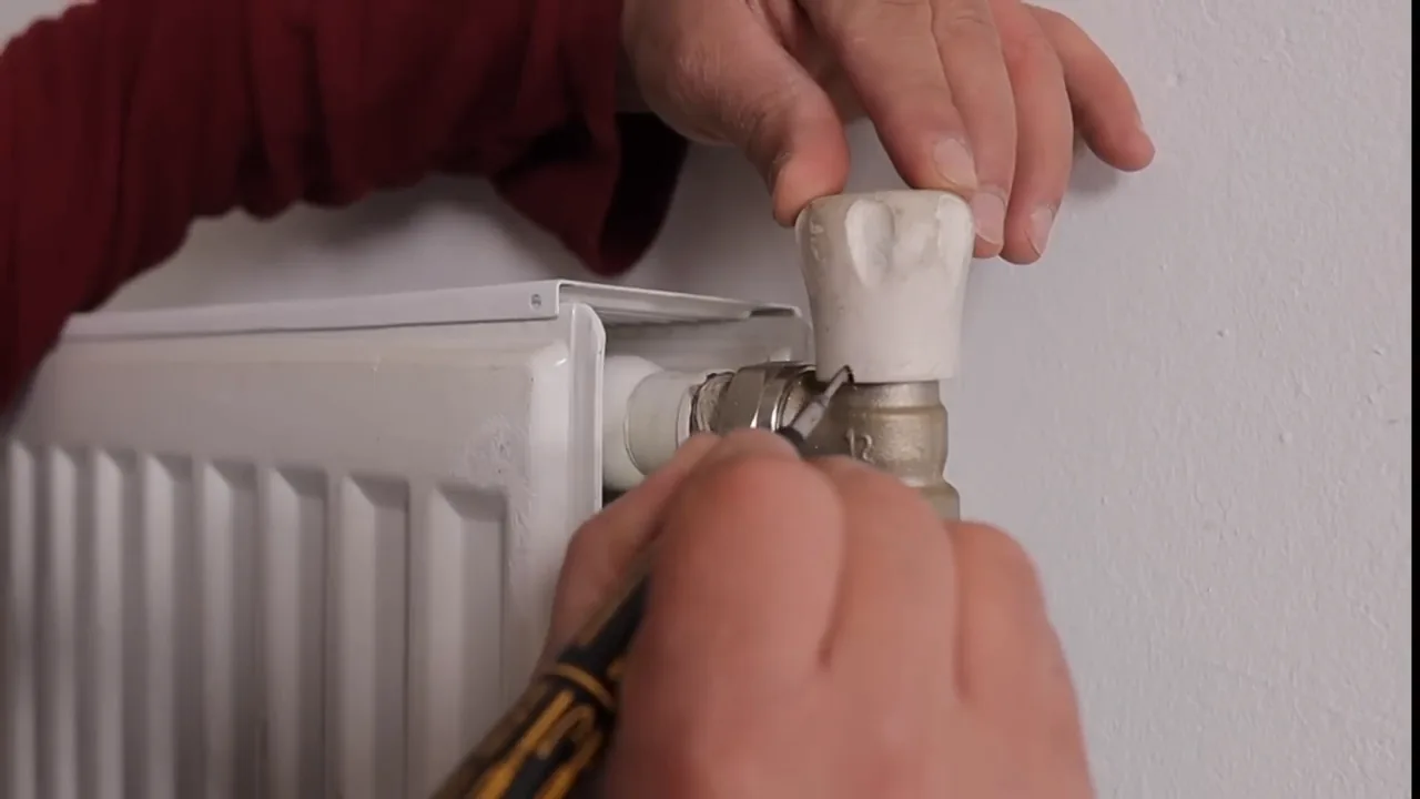Anouar zet een markering op de handknop bij de radiatorkraan