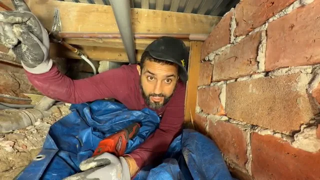 Anouar wijst de leidingroute in de lage ruimte onder de vloer aan