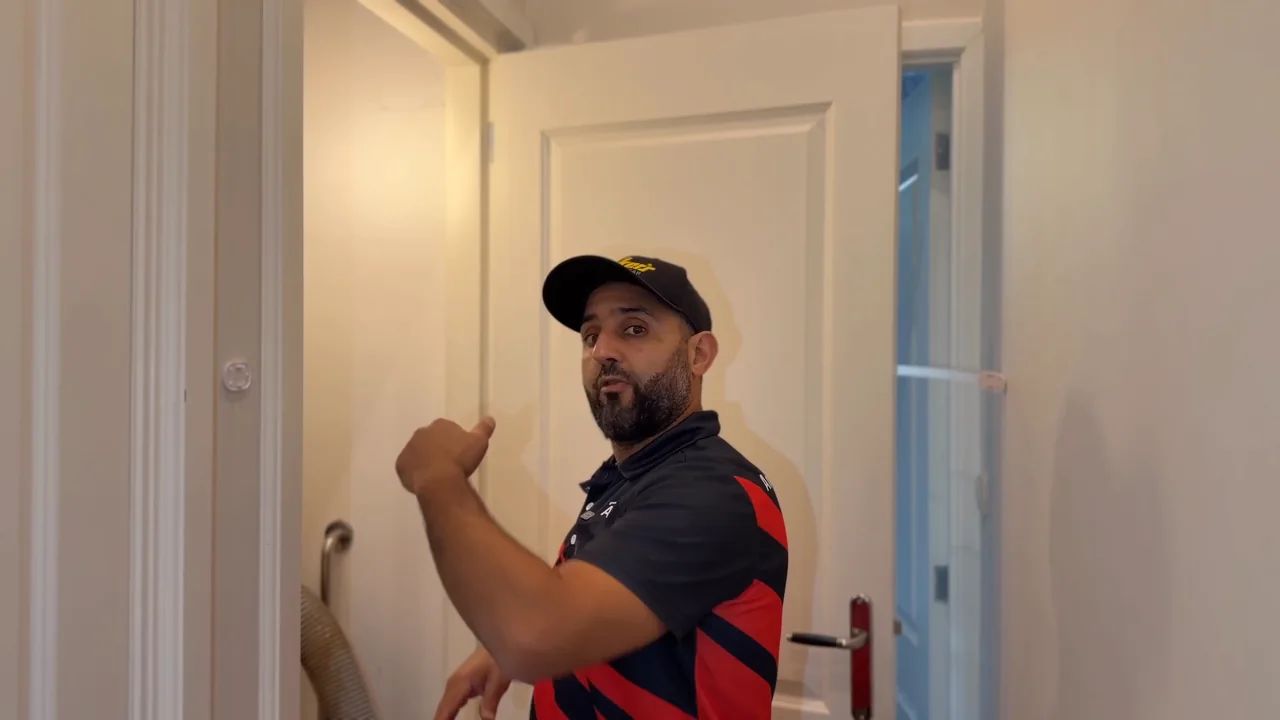 Anouar wijst naar de verborgen rookgasroute boven het plafond