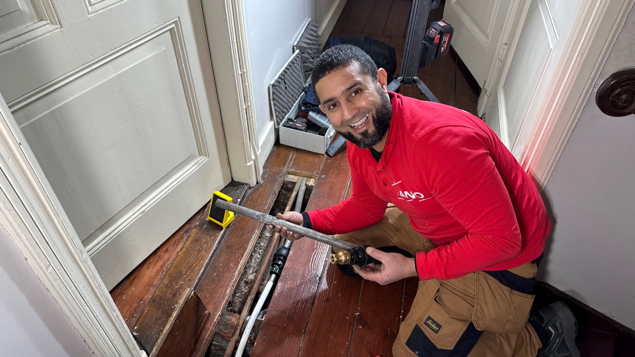 Anouar van ANO werkt aan het leidingwerk in een woning