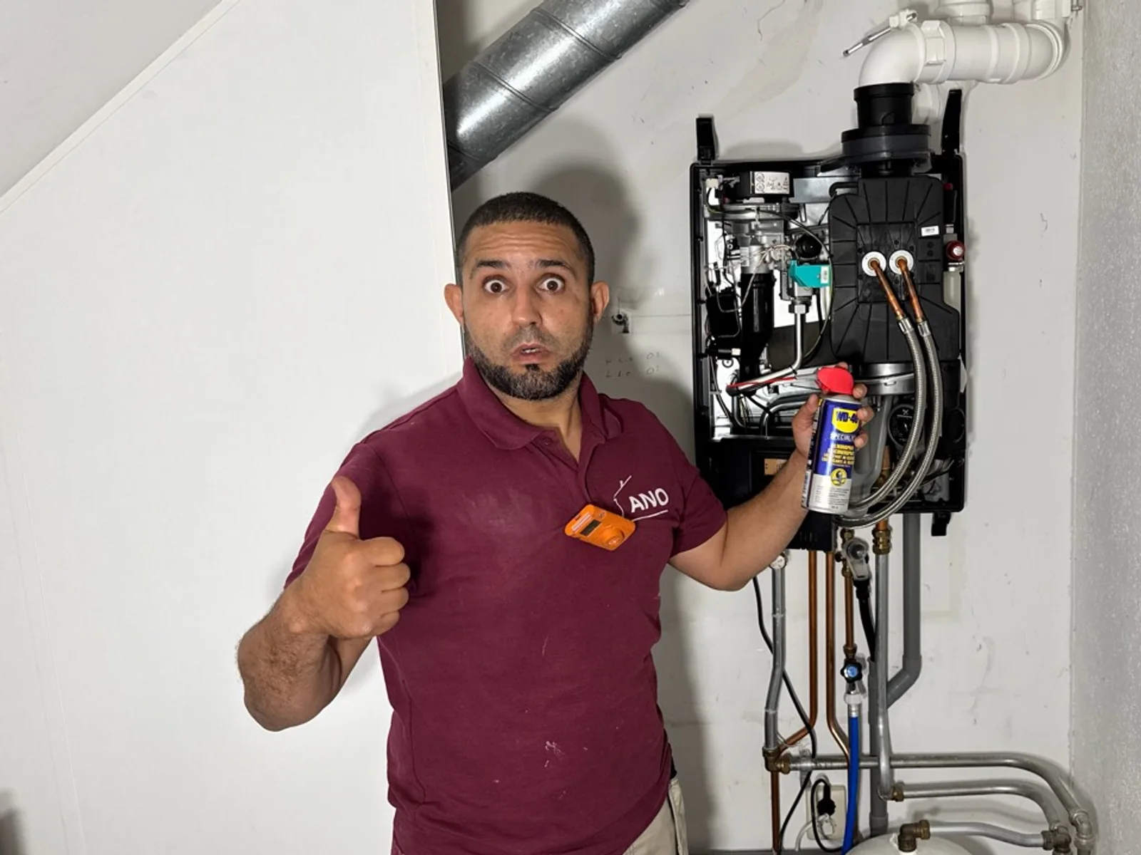 Anouar van ANO naast een geopende cv-ketel tijdens onderhoud